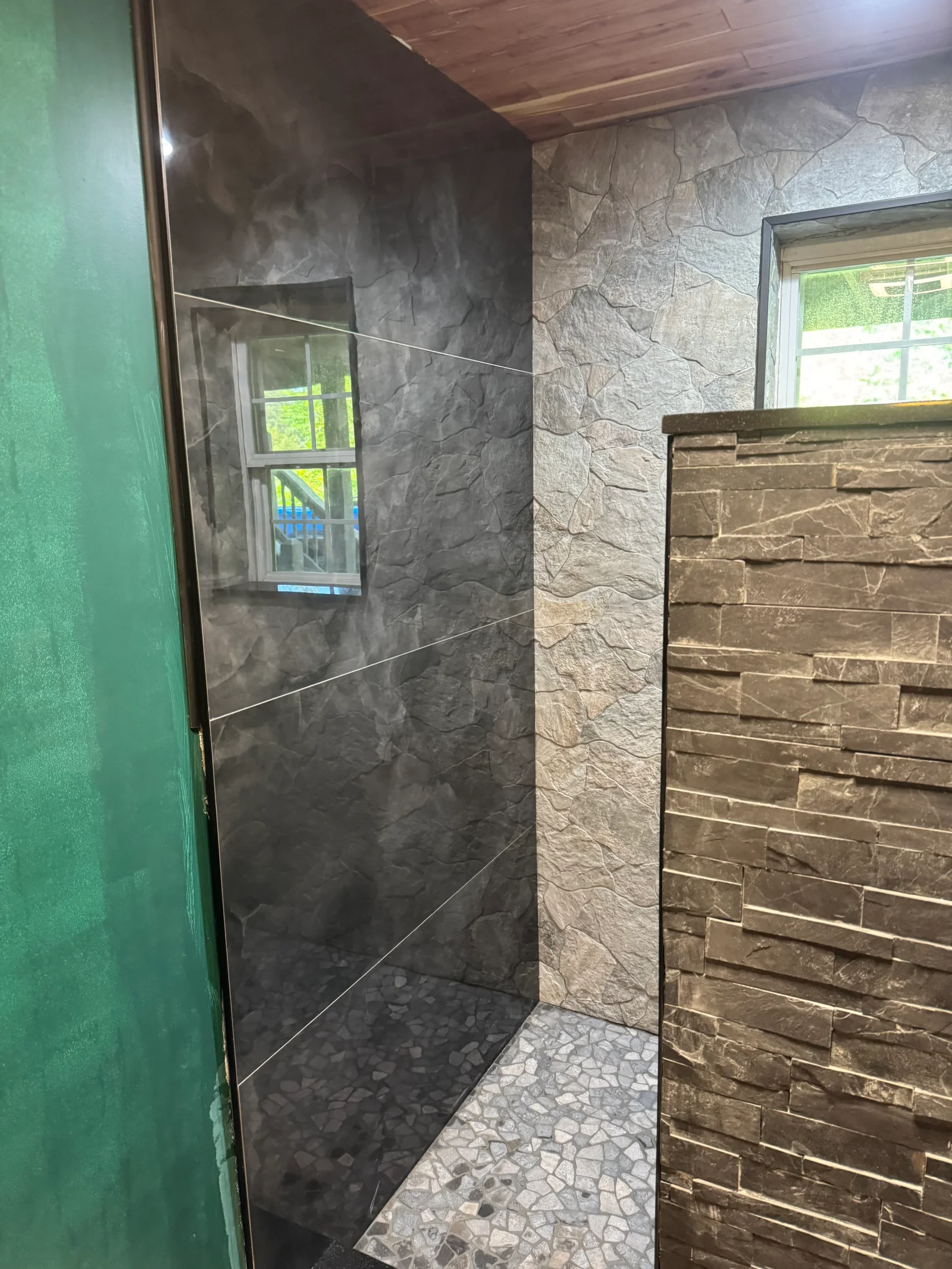 Charcoal slate shower walls with frameless glass door and stacked stone tile surround